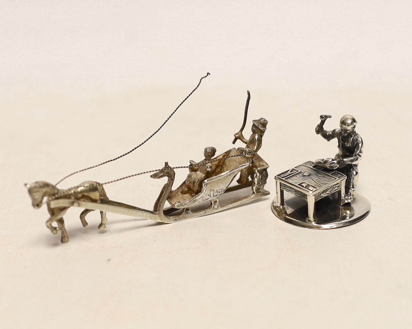A 1920's silver miniature model of a horse drawn sleigh with figures, import marks for Adolph Barsach Davis, London, 1926, 82mm and a later Italian 925 model of a cobbler.